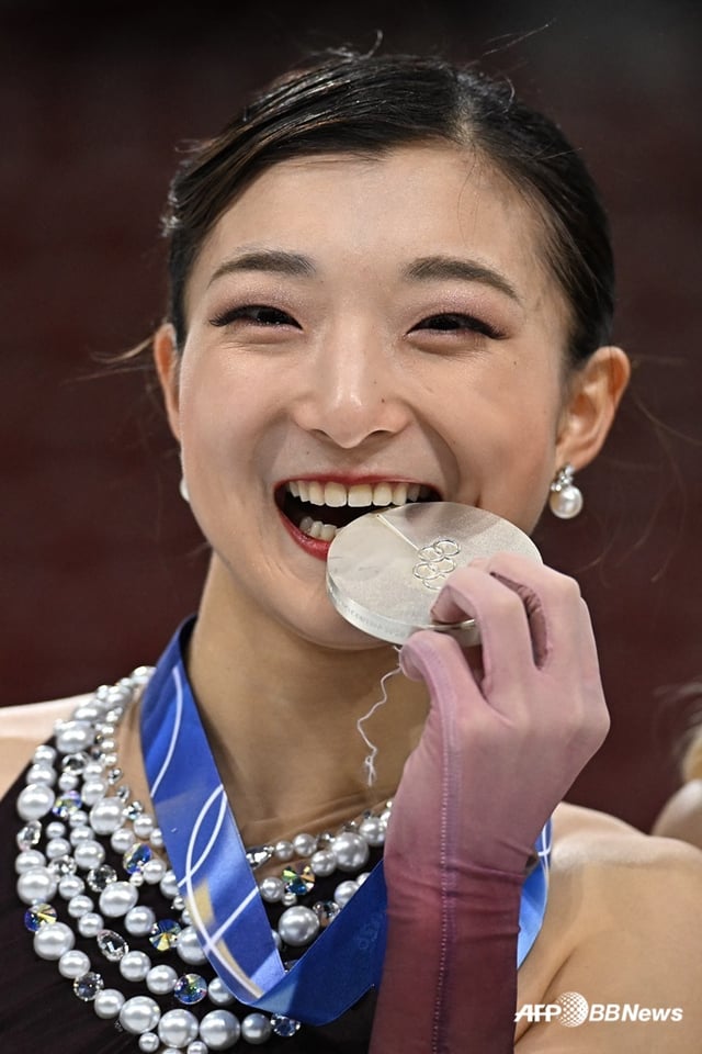 Kaori Sakamoto biting her silver medal at the Milan-Cortina d'Ampezzo Winter Olympics podium ceremony. /AFPBBNews=NEWS1