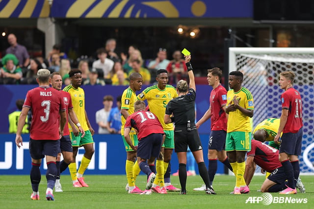 Referee Tori Penso (center) is shown holding up a yellow card. /AFPBBNews=NEWS1
