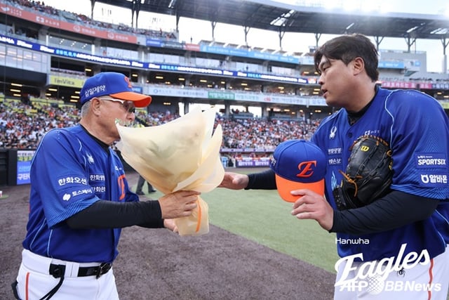 Ryu Hyun-jin de los Hanwha Eagles (derecha) recibe un ramo de flores del entrenador Kim Kyung-moon después de alcanzar el hito de 2.500 ponches acumulados entre Corea y Estados Unidos en la segunda entrada inferior durante el partido de local de la Liga KBO 2026 Shinhan SOL Bank contra los Kiwoom Heroes, celebrado el día 19 en el Daejeon Hanwha Life Ballpark. /foto=Hanwha Eagles