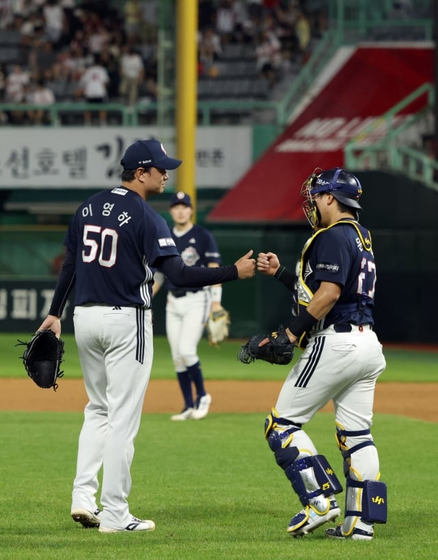 斗山(トゥサン)ベアーズの李ヨンハ(左)が30日、仁川(インチョン)SSGランダースフィールドで行われたSSGランダースと2026新韓(シンハン)SOLKBOリーグ訪問試合で勝利を確定し、捕手のユン·ジュンホとハイタッチを交わしている。 /写真=斗山ベアーズ提供