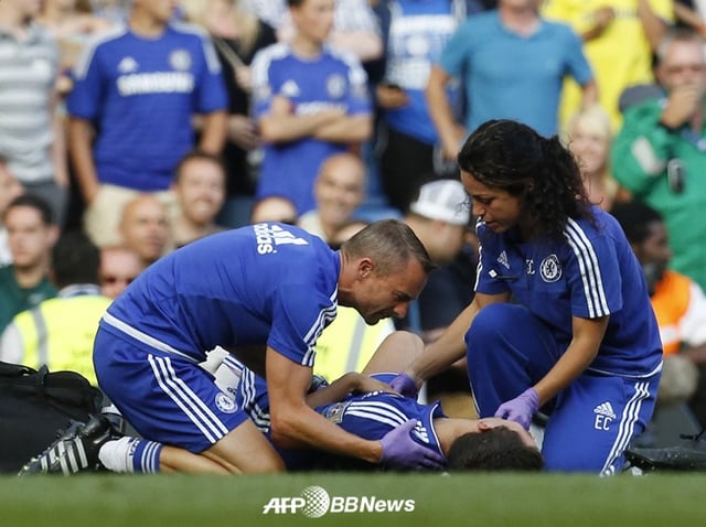 Jon Pyun (izquierda) y Eva Carneiro (derecha) revisan el estado físico de Eden Hazard, quien se encuentra tendido en el suelo. /Foto=AFPBBNews=NEWS1