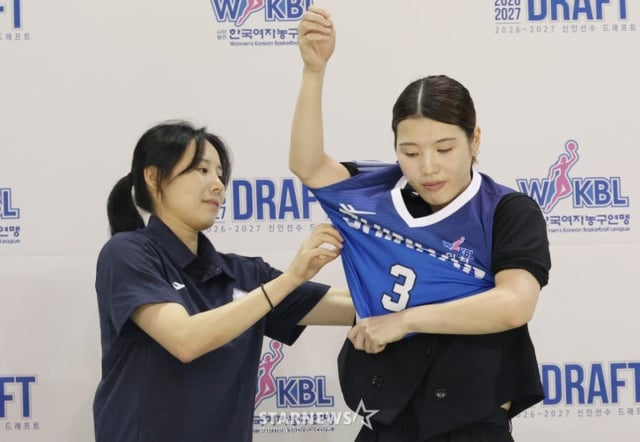 El draft de novatos del WKBL para la temporada 2026-2027 se celebró el día 19 en el Gimnasio Cheongju de la ciudad de Cheongju. Kaneda Mana (Universidad de Ciencias Humanas de Osaka) fue seleccionada como primera opción general en la primera ronda por Banco Shinhan y, tras recibir la ayuda del entrenador Choi Yoon-ah, se vistió con el uniforme. /Foto=corresponsal jefe Kim Jin-kyung.