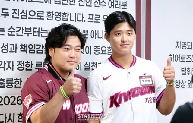 키움 1순위 지명된 박준현이 24일 고척스카이돔에서 열린 키움 2026 새내기들 환영행사에서 아버지 박석민에게 유니폼을 입혀주고 있다. 유니폼을 입은 박석민이 아들 박준현을 안고 있다. 2025.09.24. 키움 1순위 지명된 박준현이 24일 고척스카이돔에서 열린 키움 2026 새내기들 환영행사에서 송성문의 멘토링을 듣고 있다. 바로 뒤 박준현의 어버지인 박석민이 미소짓고 있다. 2025.09.24. /사진=강영조 cameratalks@