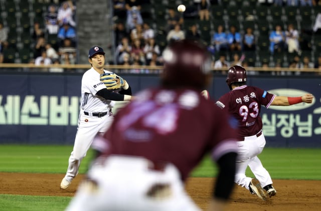 The game between Doosan Bears and Kiwoom Heroes held on the 18th at Seoul Jamsil Baseball Stadium. Doosan Bears' Kang Seung-ho (left) throws while avoiding Kiwoom's runner Yeo Dong-wook. /Photo=Doosan Bears provided