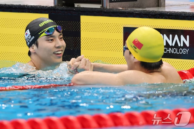 銅メダルを獲得した李周浩(イ·ジュホ、左)と金メダルの徐志亜偉(中国)が試合後、手を取り合っている。 /写真=ニュース1