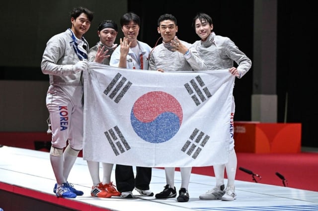 2026 아이치·나고야 아시안게임 펜싱 남자 사브르 단체전에서 4연패를 달성한 대한민국 대표팀 선수단이 국민 응원 메시지가 담긴 태극기를 들고 기념 촬영을 하고 있다./사진제공=skt