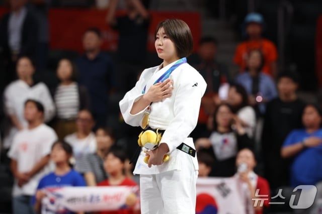 ホ·ミミが1日、日本愛知インターナショナルアリーナで開かれた2026愛知·名古屋アジア大会柔道女子57㎏級決勝授賞式で金メダルを首にかけて愛国歌に合わせて胸に手を当てている。 /写真=ニュース1