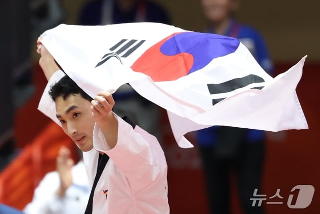 Yoon Gyu-seong celebra su victoria sosteniendo la bandera surcoreana durante la final de la modalidad individual masculina de Poomsae en Taekwondo de los Juegos Asiáticos de Aichi-Nagoya 2026, celebrada el día 1 en el Gimnasio de Toyohashi, en la prefectura de Aichi, Japón. /Foto=News1