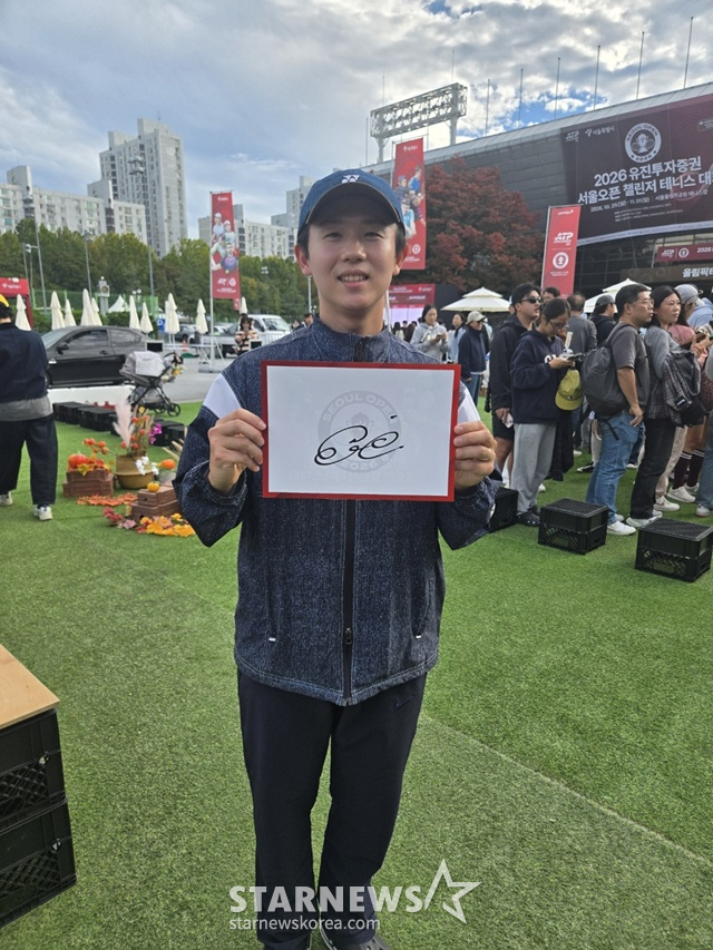 테니스 팬 김태형 씨가 25일 서울오픈에서 마린 칠리치에게 받은 사인을 들어 보이며 환하게 웃고 있다. /사진=이원희 기자.