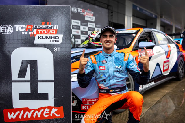 Driver Mikel Azcona, who took first place, poses in front of his car after securing the win.