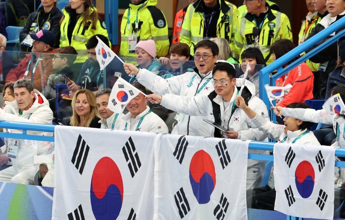12日（当地时间），韩国文化体育观光部部长崔辉映（中）在意大利科尔蒂纳丹佩佐冰壶奥林匹克体育场举行的韩国和意大利的2026米兰·科尔蒂纳丹佩佐冬季残奥会轮椅冰壶混合队预选赛中，正在为韩国选手加油助威。 =照片:韩国文化体育观光部。