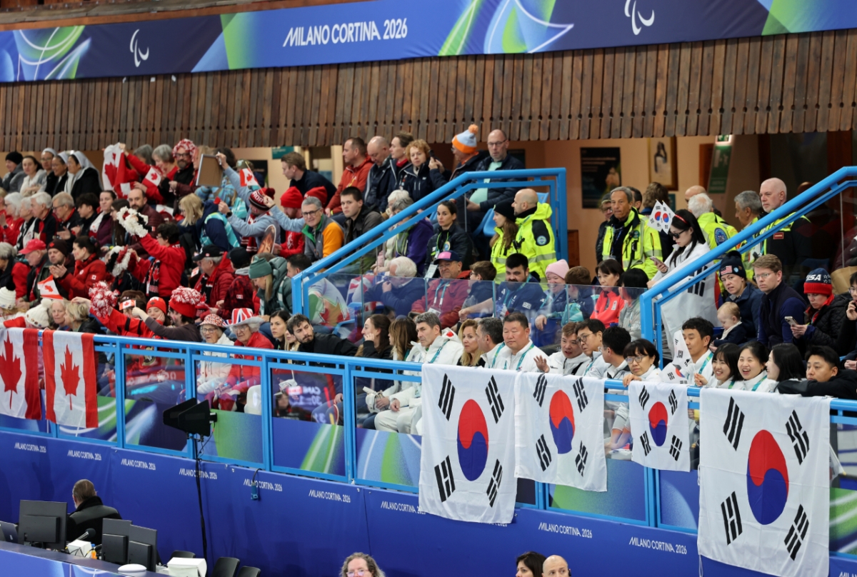 图为1月12日（当地时间），在意大利科尔蒂纳丹佩佐冰壶奥林匹克体育场举行的韩国和意大利的2026米兰·科尔蒂纳丹佩佐冬季残奥会轮椅冰壶混合队预选赛中，文化体育观光部部长崔辉映（音）和相关人士正在为韩国选手加油助威。 =照片:韩国文化体育观光部。