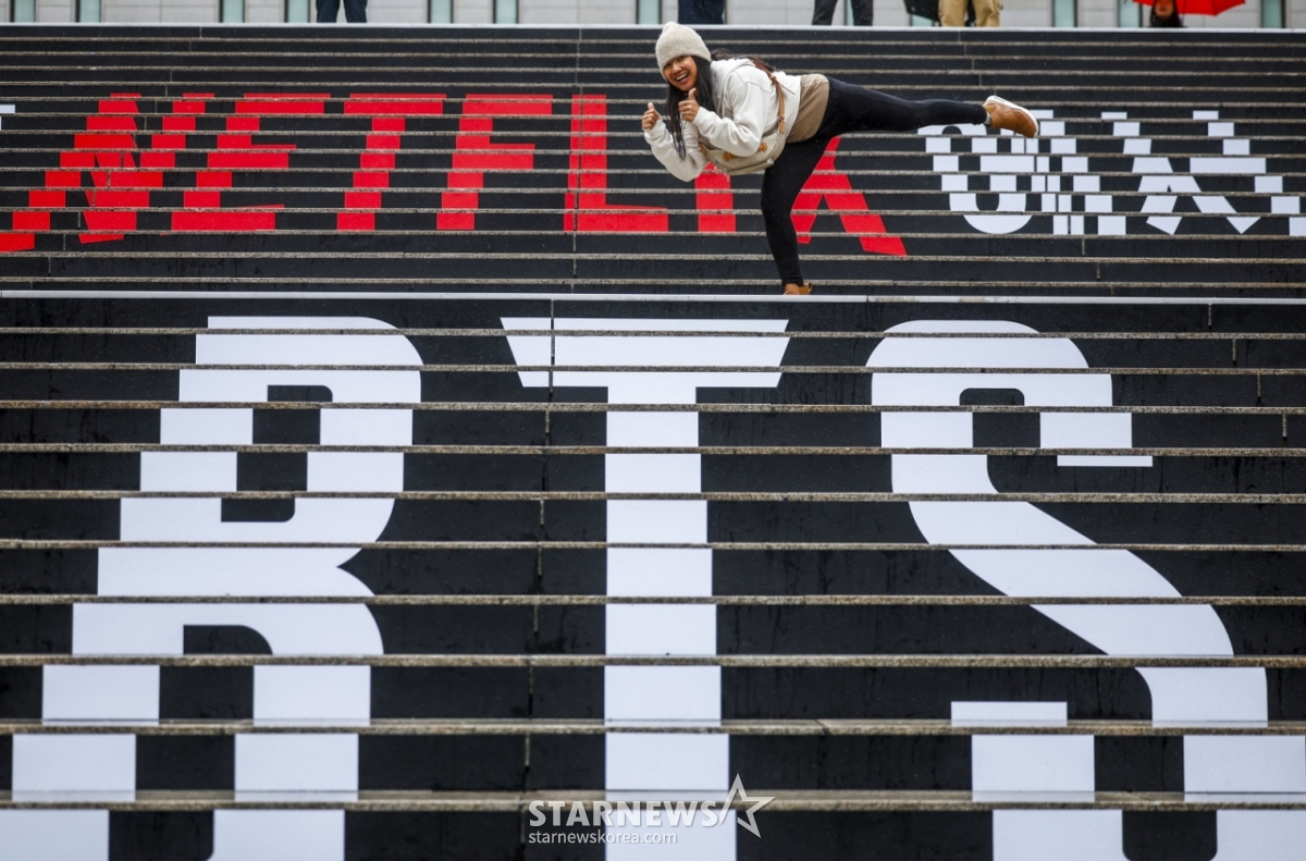 【ソウル=ニューシス】チョン·ビョンヒョク記者=BTS（BTS）のソウル光化門（クァンファムン）広場カムバック公演を控えた18日、ソウル鍾路区世宗（チョンログ·セジョン）文化会館の階段を訪れた外国人ファンがBTSラッピングの前で写真を撮っている。 2026.03.18.jhope@newsis.com /写真=チョン·ビョンヒョク